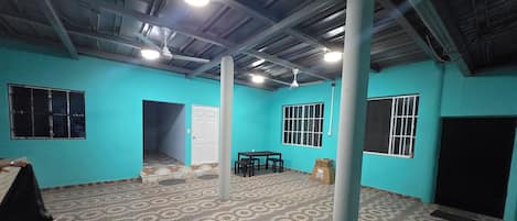 A room with teal walls, a patterned floor, a ceiling fan, and a table with chairs.