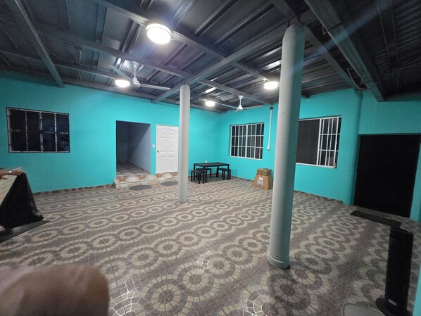 A room with teal walls, a patterned floor, a ceiling fan, and a table with chairs.