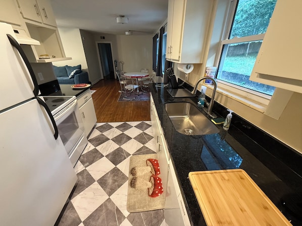 A compact kitchen with a black countertop, a sink, and a wooden cutting board. - The Heron Haven Spacious/Quiet/Charming 1950 House in Pensacola (Pensacola)