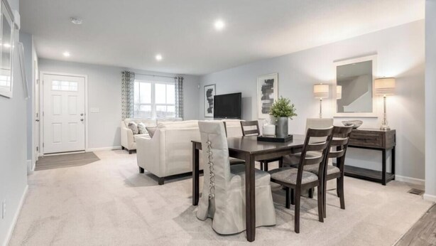 Een moderne woonkamer met een bank, een eettafel met stoelen, een televisie en een lamp.