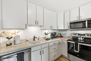 Eine moderne Küche mit weißen Schränken, Edelstahlgeräten und einer Arbeitsplatte aus Granit.