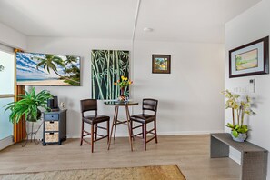 A modern living room with a flat-screen TV, two chairs, a coffee table, and a large painting of a beach scene. - New Listing! My Perfect Stays! (Lahaina)