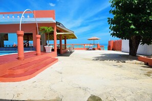 Propiedad frente a la playa con un patio cubierto, piscina y vista al océano.