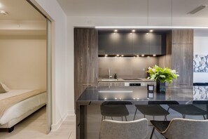 A modern kitchen with a central island, dark wood cabinetry, and a built-in stove. - Luxe Nobu | 2BR + Private 750 SqFt Terrace in the Heart of Toronto (Toronto)