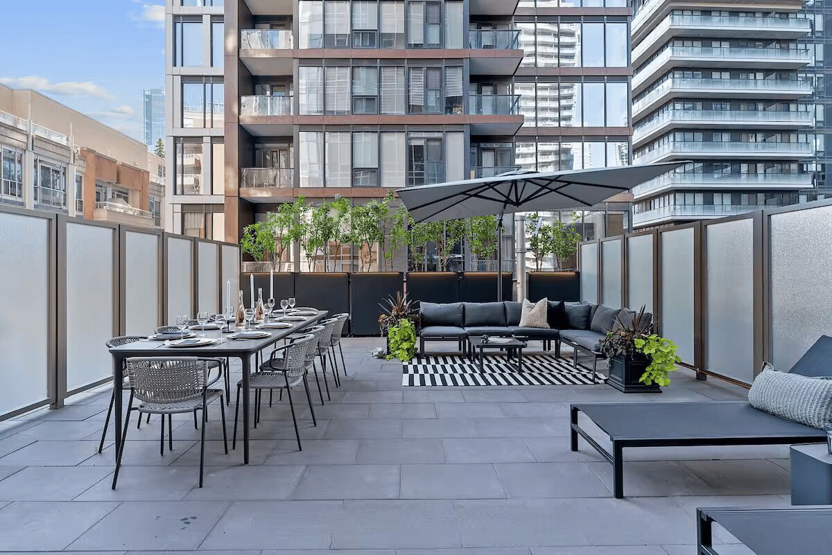 Een terras met een eettafel voor zes personen, omringd door stoelen en een bank met een bijzettafeltje.