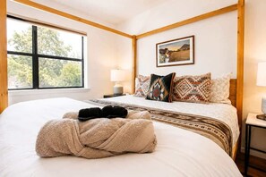 A hotel room with a large bed, a window with a view of trees, a bedside lamp, and a framed picture on the wall. - Old Town Buffalo+Private Hot Tub+Near Old Town+Pet Friendly! (Albuquerque)