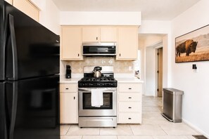 A modern kitchen with a black refrigerator, stainless steel stove, and microwave. - Old Town Buffalo+Private Hot Tub+Near Old Town+Pet Friendly! (Albuquerque)