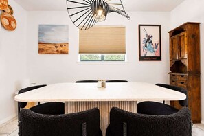 A dining area with a round table, black chairs, a wooden cabinet, and artwork on the walls. - Old Town Buffalo+Private Hot Tub+Near Old Town+Pet Friendly! (Albuquerque)