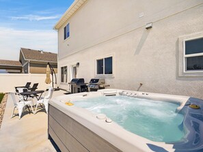 Ein Garten mit Whirlpool, Gartenmöbeln und Grill.
