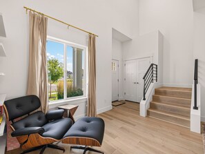 Ein modernes Interieur mit Holzboden, einer schwarzen Ledercouch, einem kleinen Holztisch und einer Treppe mit schwarzer Geländer.