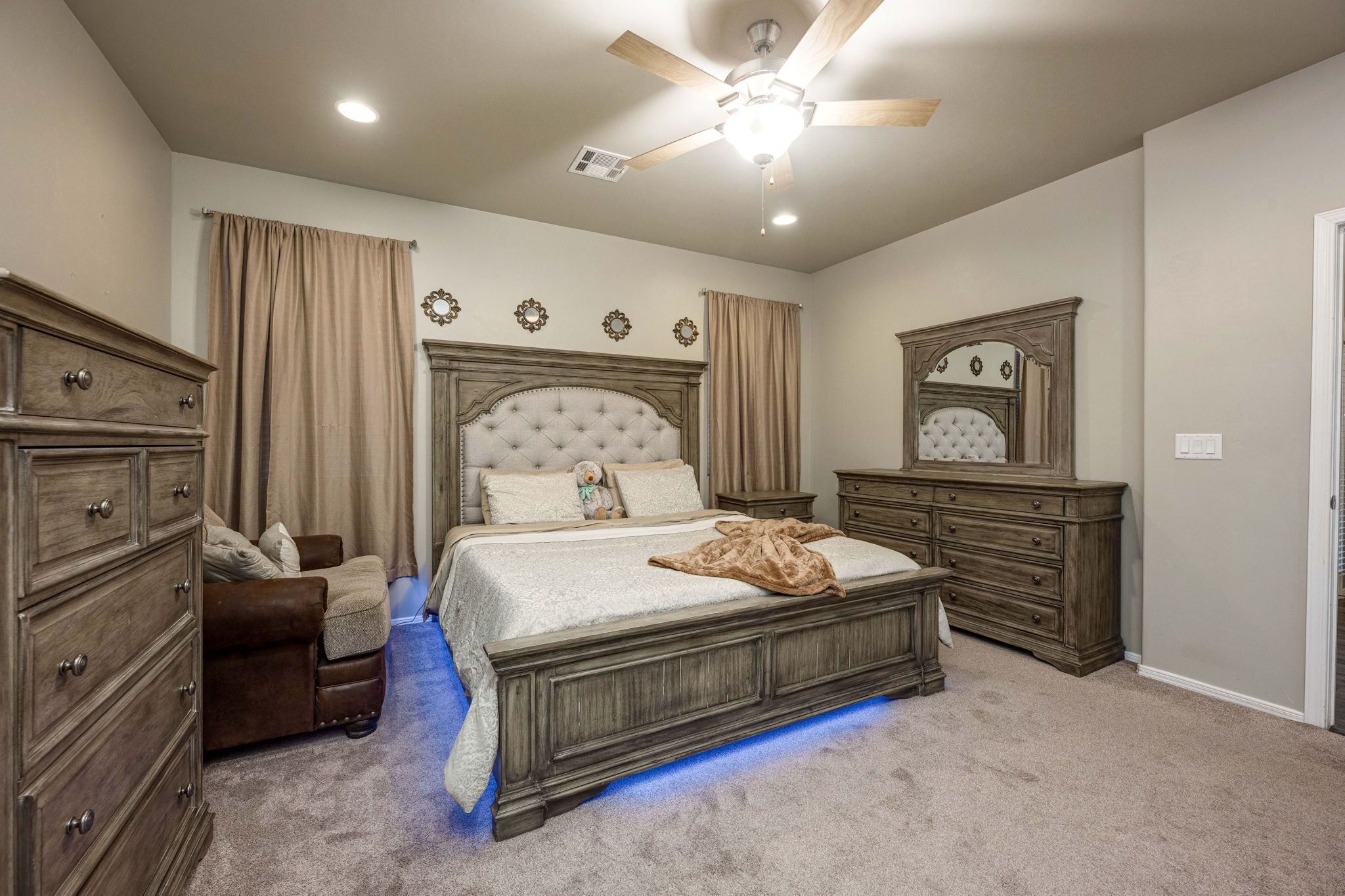 A bedroom with a bed, dresser, nightstand, and a ceiling fan.