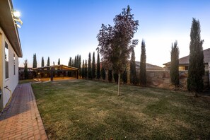 Una propiedad residencial con un césped bien cuidado, una zona de estar exterior cubierta y un muro de piedra.