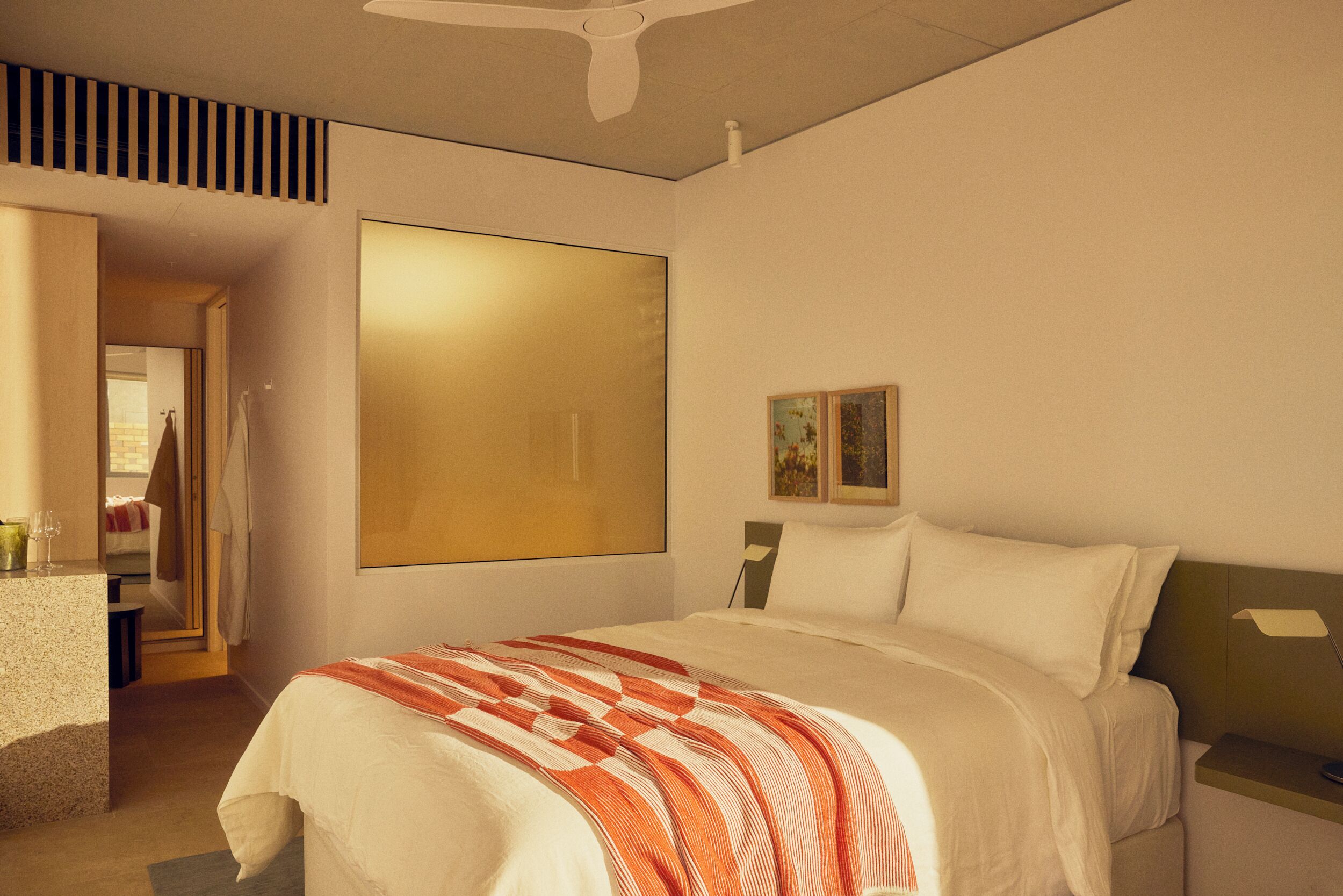 Une chambre à coucher comprenant un lit, une table de chevet, une fenêtre et une porte donnant sur une autre pièce.
