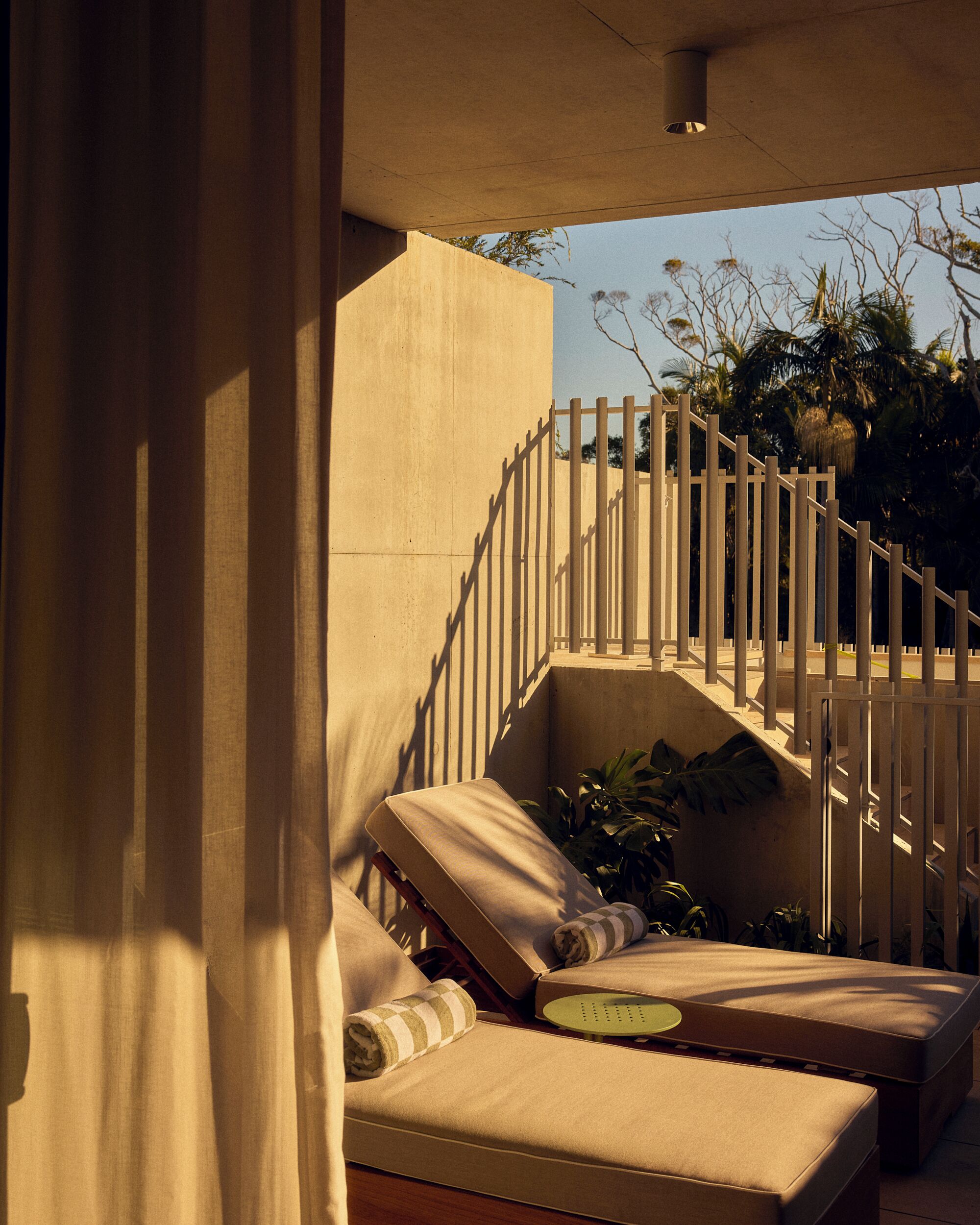 A sunlit outdoor seating area with lounge chairs and a staircase.