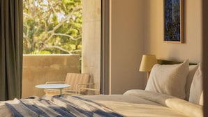 Una habitación de hotel con cama, ventana, un cuadro y una mesita con sillas.