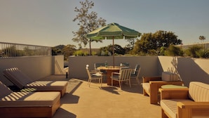Terraza en la azotea con mobiliario exterior, una mesa y una sombrilla.