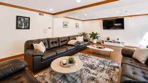 Una sala de estar moderna con un sofá de cuero, una mesa de centro y un televisor montado en la pared.