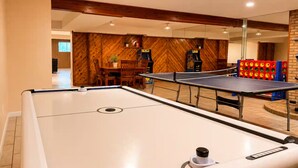 Una mesa de billar en una habitación con paredes de madera y un comedor al fondo.