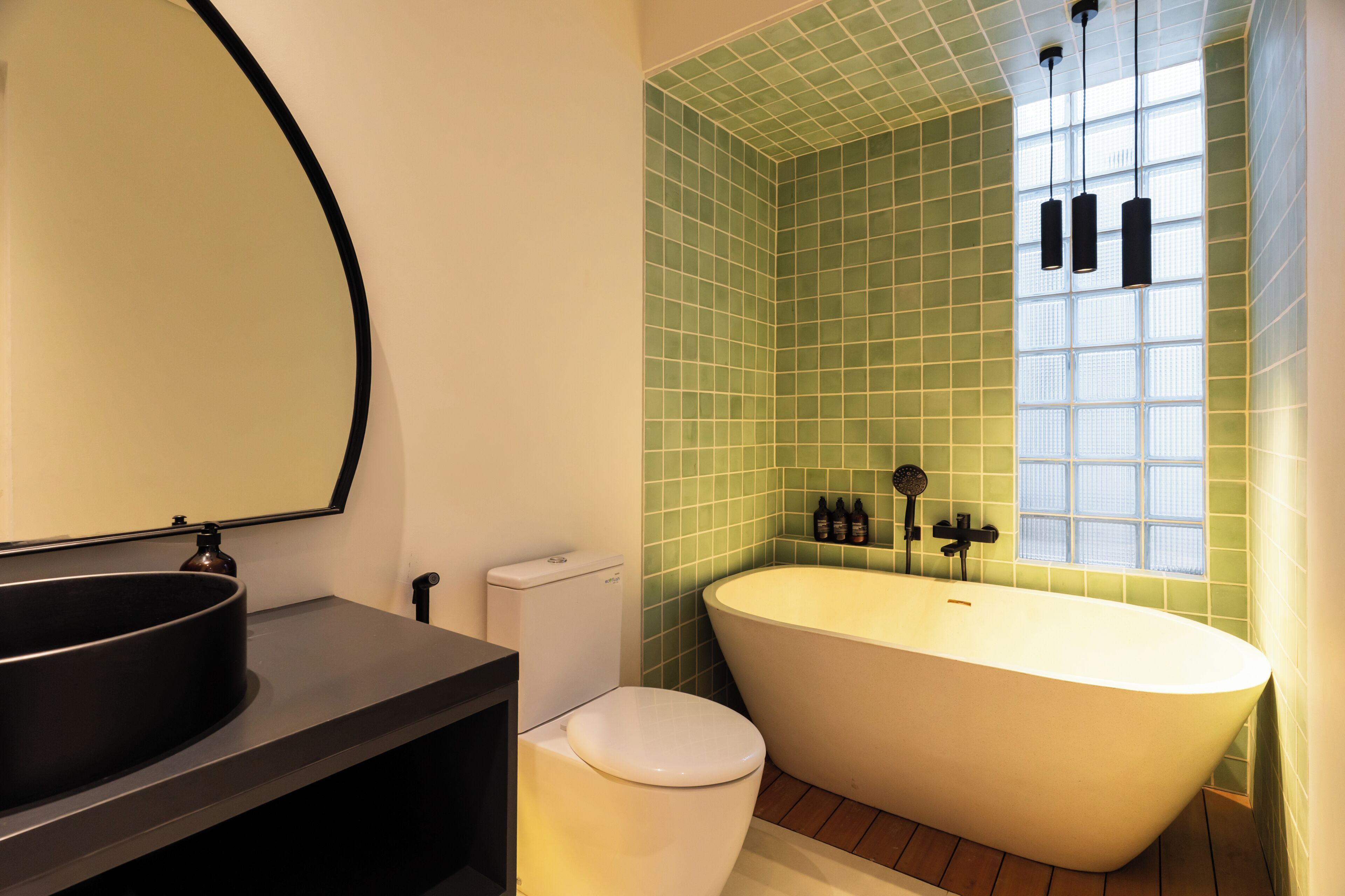 A bathroom with a freestanding bathtub, a toilet, a sink with a mirror, and a window with a view.