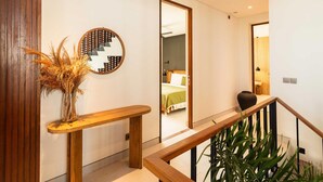 A modern interior with a wooden bench, a mirror, and a staircase with a railing.