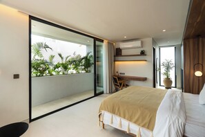 Un dormitorio moderno con una cama grande, un escritorio y vistas a un balcón con plantas.