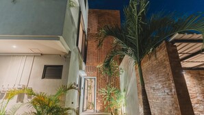 A narrow alleyway with a brick wall, a metal gate, and potted plants.