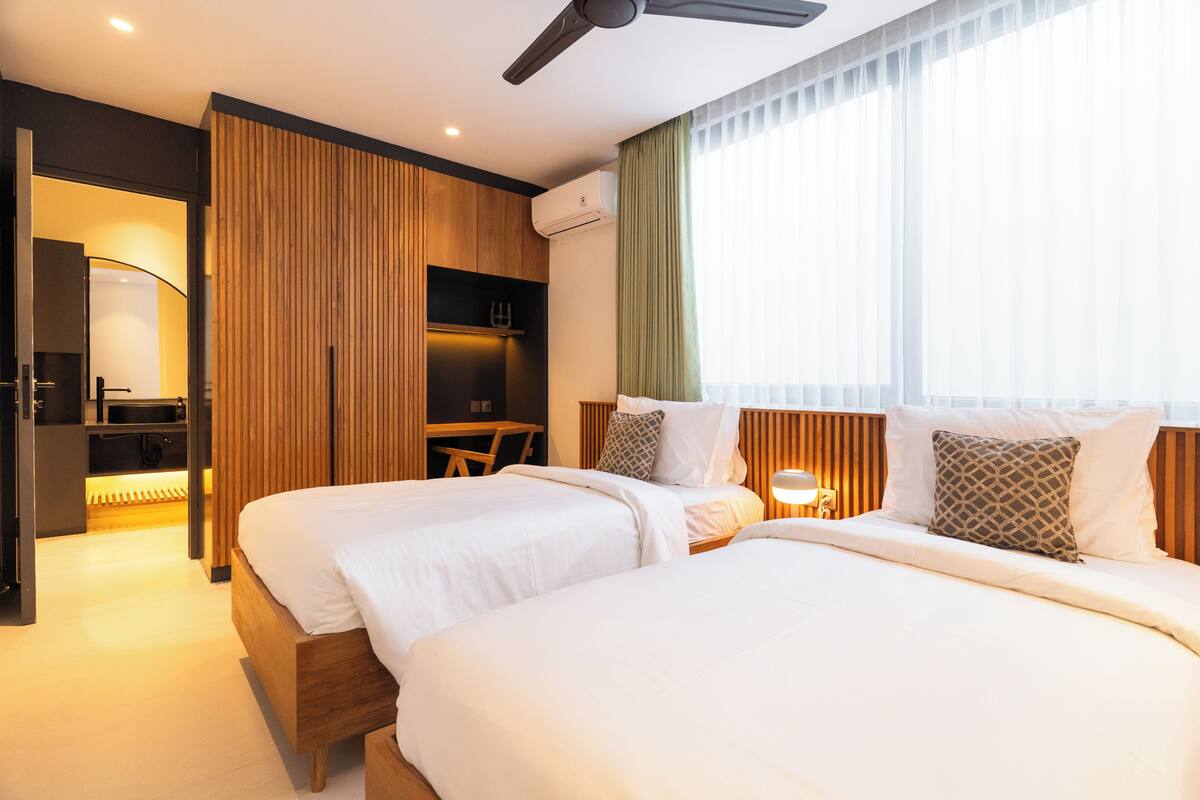 Una habitación de hotel con dos camas, un escritorio y un armario.