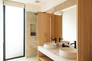 Un baño moderno con dos lavamanos redondos, un espejo grande y paneles de madera.