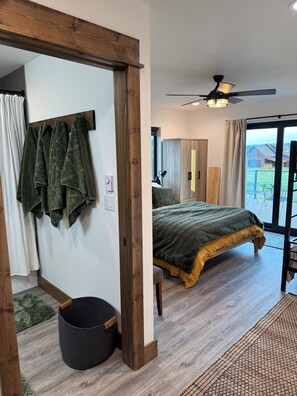 Ein Schlafzimmer mit einem Bett, einem Holzschrank, einem Deckenventilator und Blick ins Freie.