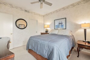 A bedroom with a bed, a nightstand, a lamp, a chair, a ceiling fan, and a framed picture on the wall. - 4BR Desert Retreat on the Golf Course Desert Falls (Palm Desert)