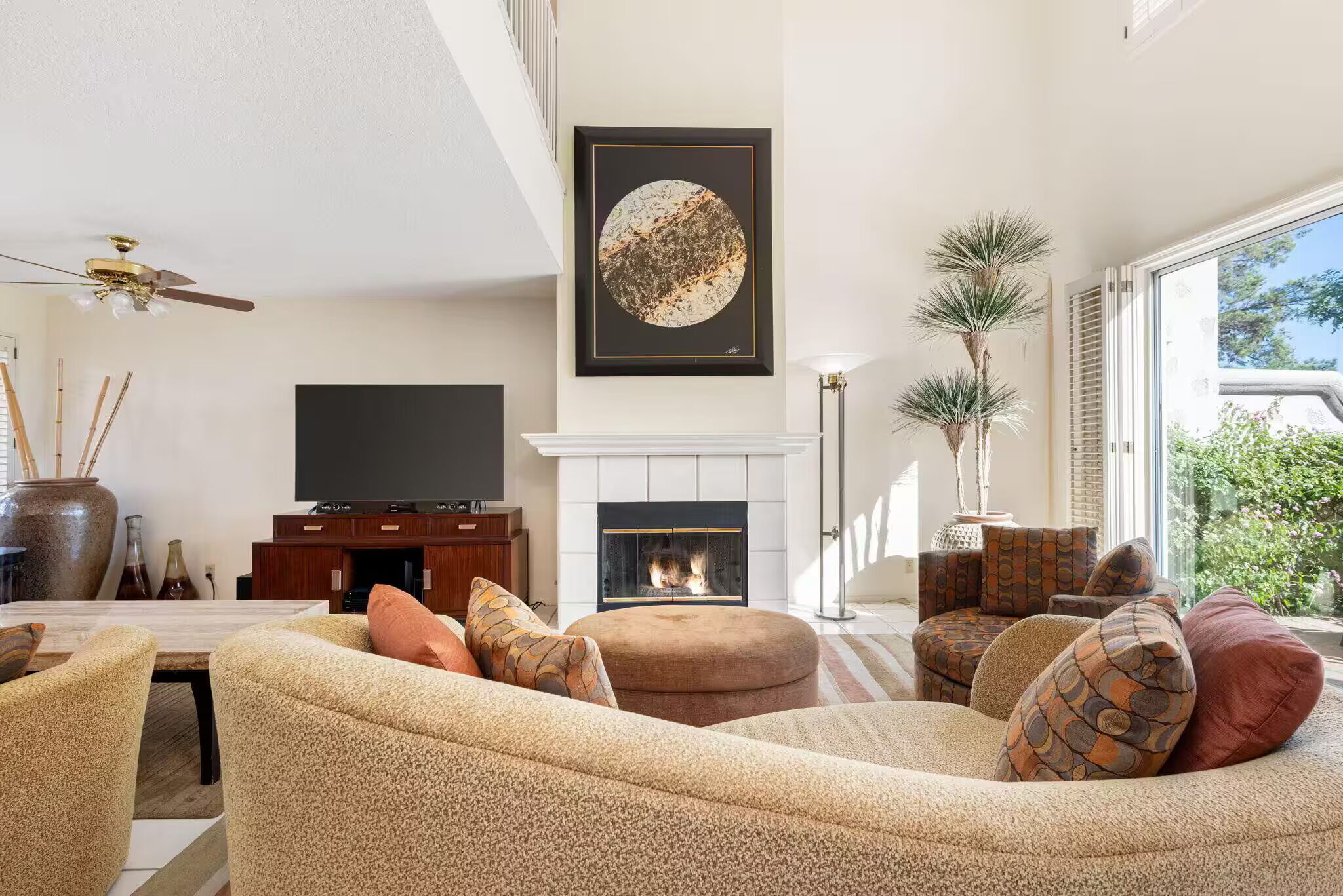 A living room with a fireplace, a television, and a large window.