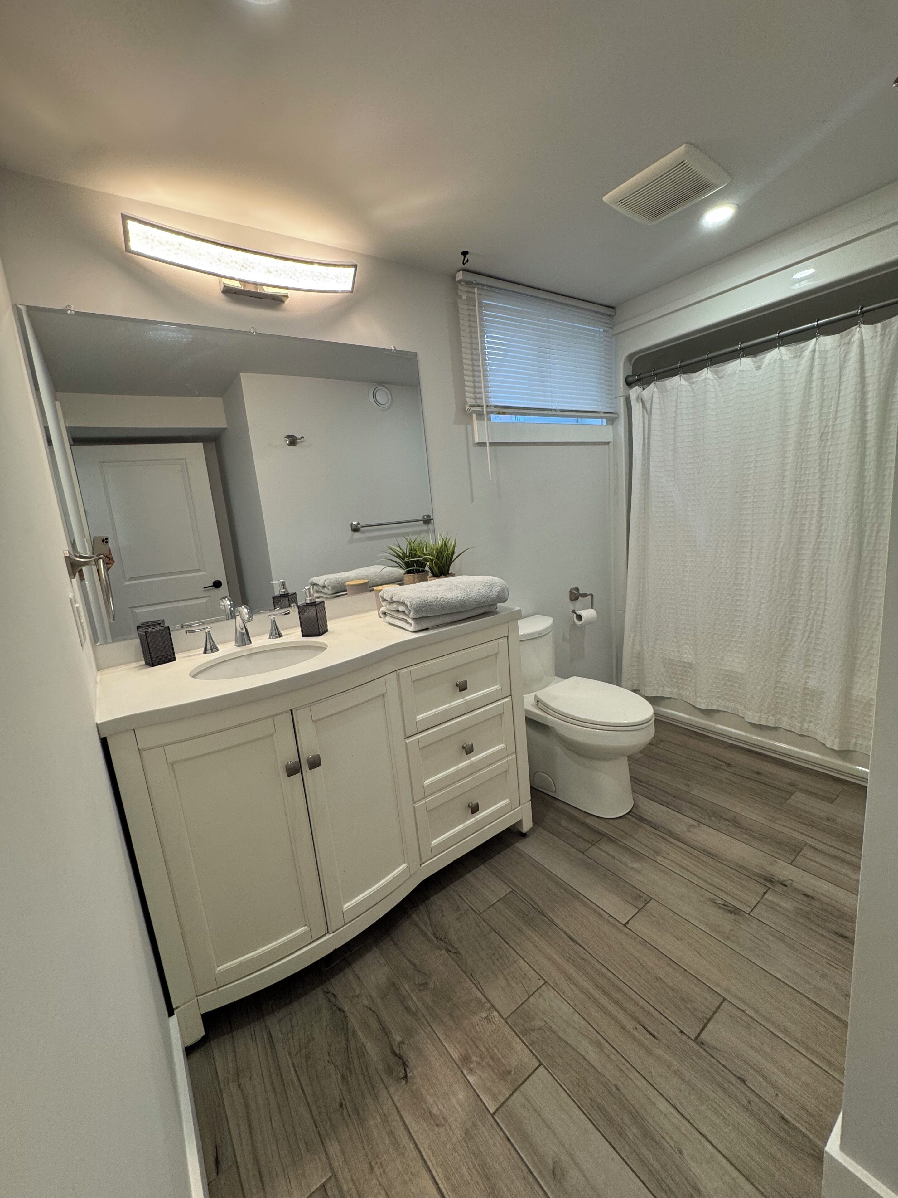 A modern bathroom with a white vanity, a toilet, and a shower curtain.