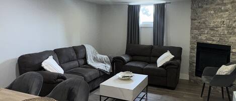 A modern living room with a sofa set, a coffee table, and a fireplace.