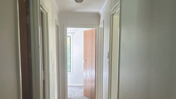 Un couloir doté d’un plancher en bois, de murs blancs et de portes donnant sur d’autres pièces.