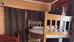Una cama litera de madera con una cama inferior y una cama individual con cabecera.