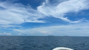 Cielo despejado con nubes sobre un mar tranquilo.
