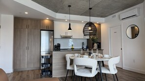 A modern kitchen with a built-in refrigerator, a dining area with a round table and white chairs, and a ceiling with recessed lighting. - La Cachette du 11e | 2 bedrooms | Parking | Pool | Old Quebec (Quebec)