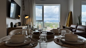 Uma zona de refeições com uma mesa posta para quatro pessoas, vista da cidade e design de interiores moderno.