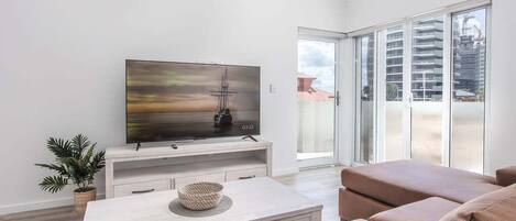 A modern living room with a flat-screen TV, a coffee table, and a sofa.