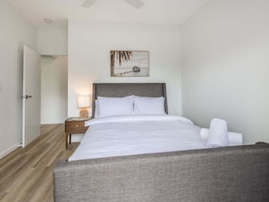 A bedroom with a bed, a nightstand, a lamp, and a wall-mounted picture. - The Laneway Villas - Central Apartments in the heart of Burleigh Heads - Unit 3 (Gold Coast)