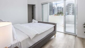 Een slaapkamer met een bed, nachtkastje, lamp en een schuifdeur naar een balkon.