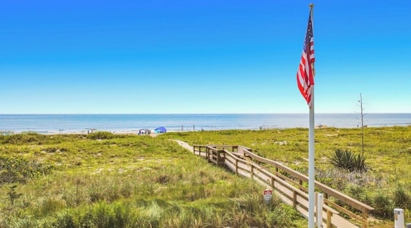 Ein Strand mit einer Holzpromenade, die zu einem Fahnenmast mit der US-amerikanischen Flagge führt.