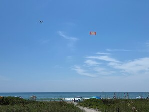 Ein Strand mit Sonnenschirmen, einem Weg und einem Schild in der Ferne.