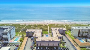 A beachfront hotel with multiple buildings, a swimming pool, and a beach in the background. - Ocean View Beach Condo w/ Heated Pool in Cocoa Beach (Cocoa Beach)