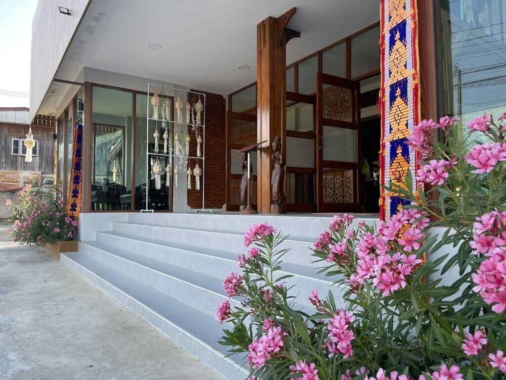 Un edificio de diseño tradicional, con fachada de madera, una escalera que conduce a una entrada de vidrio y una pared decorativa con diseños intrincados.