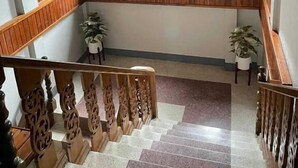 Una escalera de madera con un candelabro, plantas en macetas y un panel decorativo en la pared.