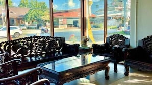 Una habitación con amplios ventanales, una mesa de centro de madera y sillas ornamentadas.