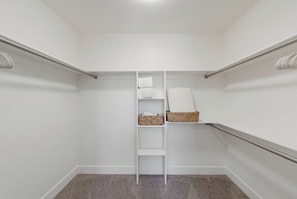 Ein begehbarer Kleiderschrank mit einer Metallleiter, Regalen und Körben.