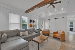 Una sala de estar con sofá, dos sillones, una mesita de centro y un ventilador de techo.