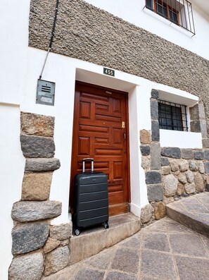 A stone facade with a wooden door, a black suitcase, and a number '455' sign.